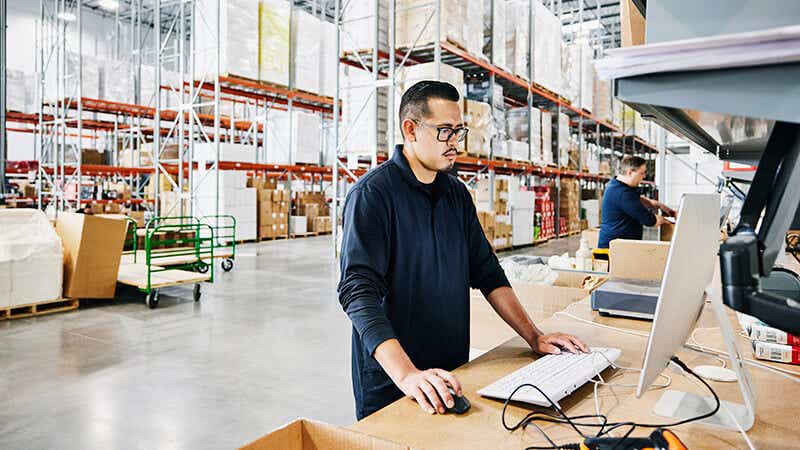 A person standing in front of a computer inside a warehouse.