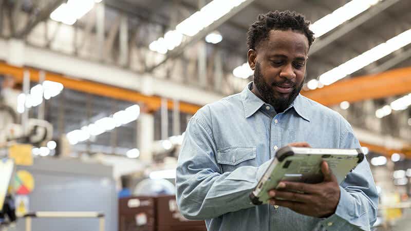 A man using a device to track materials, components and goods.